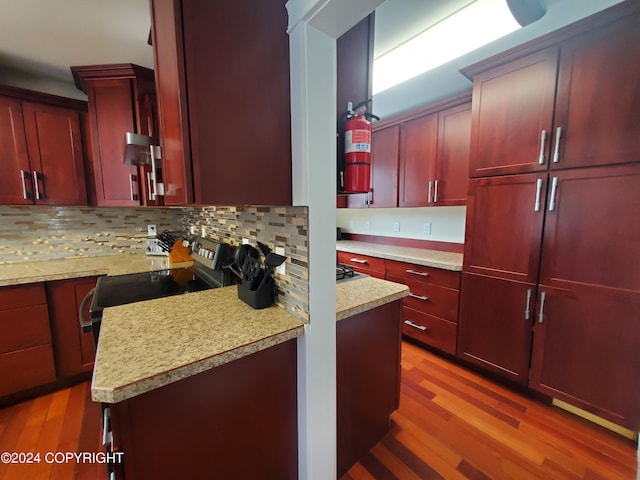 kitchen featuring light stone counters, tasteful backsplash, stainless steel electric range oven, and light hardwood / wood-style flooring