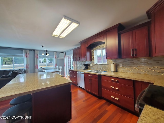 kitchen featuring dark wood-type flooring, stainless steel dishwasher, pendant lighting, a center island, and sink