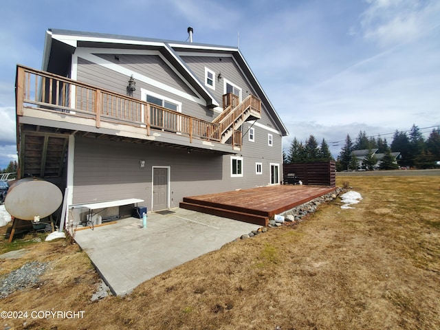 back of property with a deck, a patio area, and a yard