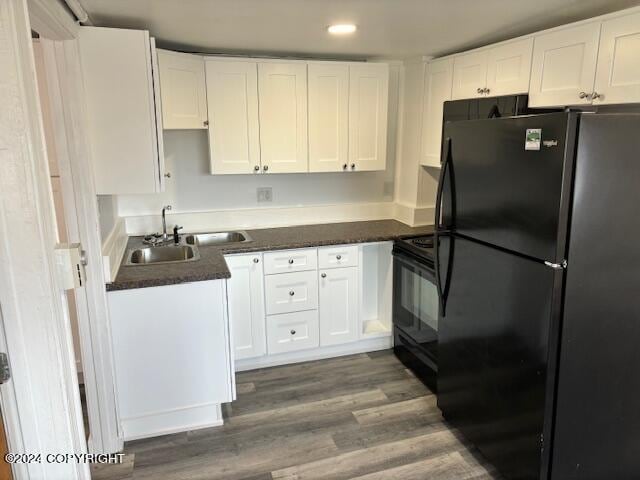 kitchen featuring white cabinetry, dark wood-type flooring, black appliances, and sink