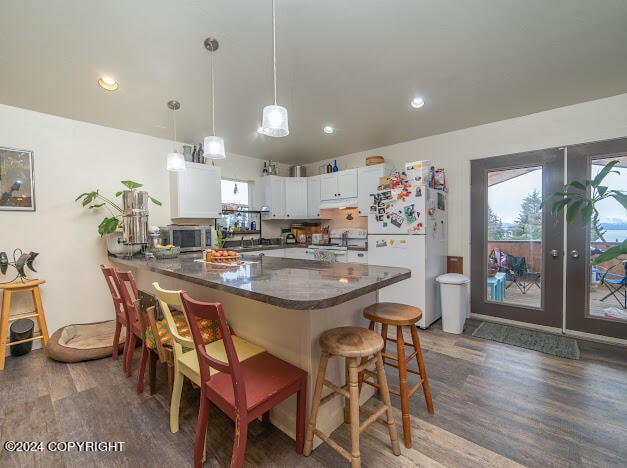 kitchen featuring white fridge, a kitchen bar, white cabinetry, plenty of natural light, and hardwood / wood-style flooring