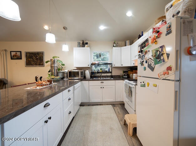 kitchen with dark stone counters, white cabinets, white appliances, and light hardwood / wood-style floors