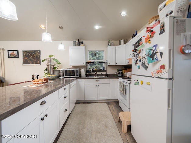 kitchen with decorative light fixtures, white appliances, hardwood / wood-style flooring, white cabinetry, and sink