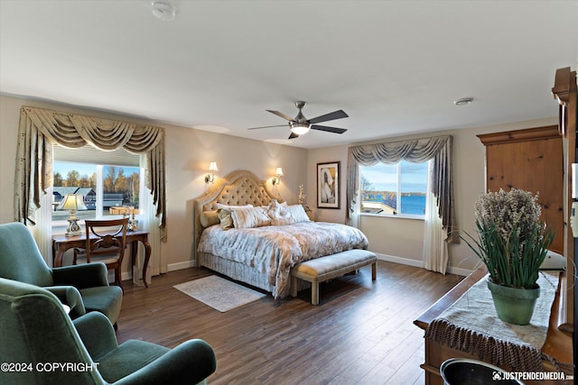 bedroom with hardwood / wood-style flooring, a water view, and ceiling fan