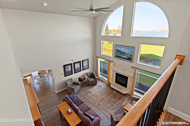 living room with a premium fireplace, ceiling fan, high vaulted ceiling, and dark wood-type flooring