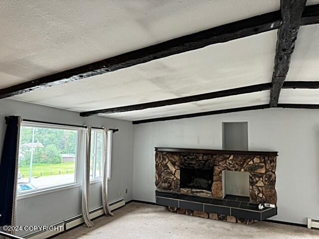 unfurnished living room featuring a baseboard heating unit, a fireplace, a textured ceiling, and beamed ceiling