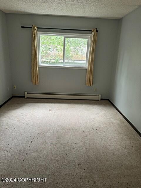 empty room with a baseboard heating unit and a textured ceiling