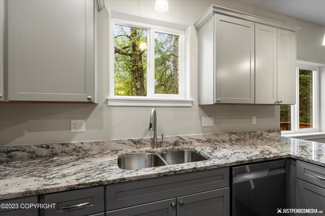 kitchen with light stone counters, white cabinets, sink, gray cabinetry, and stainless steel dishwasher