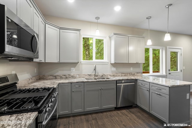 kitchen featuring appliances with stainless steel finishes, hanging light fixtures, a healthy amount of sunlight, sink, and dark hardwood / wood-style flooring