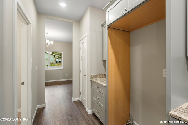 kitchen featuring decorative light fixtures, light stone countertops, gray cabinets, dark hardwood / wood-style flooring, and a notable chandelier