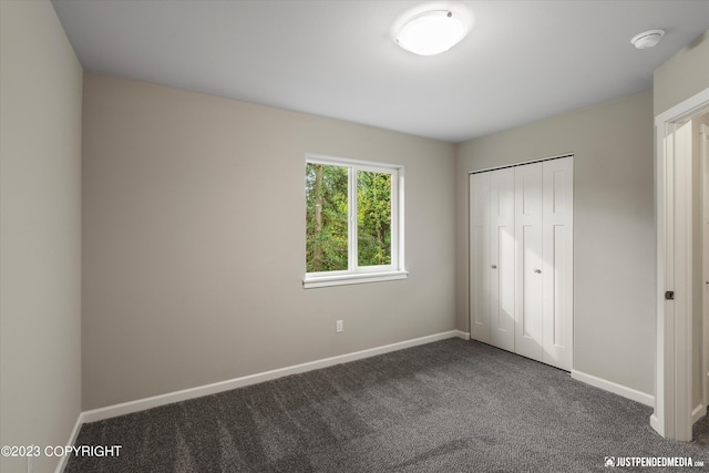 unfurnished bedroom with dark carpet and a closet