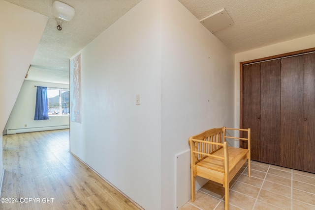 corridor with a textured ceiling, vaulted ceiling, light hardwood / wood-style floors, and a baseboard heating unit