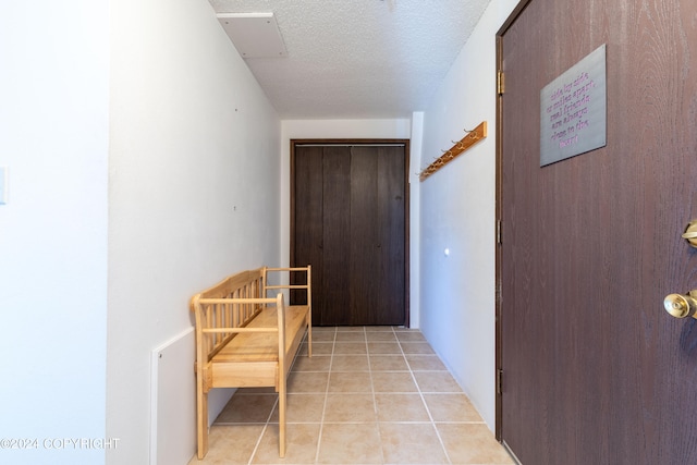 hallway featuring a textured ceiling and light tile flooring