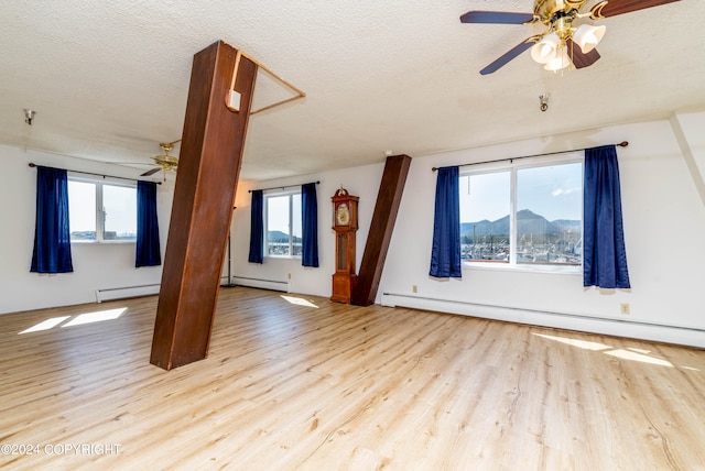 spare room with hardwood / wood-style floors, baseboard heating, and a textured ceiling