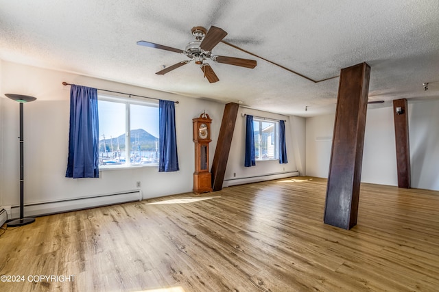 spare room featuring wood-type flooring, a textured ceiling, ceiling fan, and a baseboard heating unit