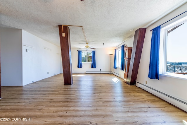 empty room featuring a textured ceiling, wood-type flooring, ceiling fan, and a baseboard radiator