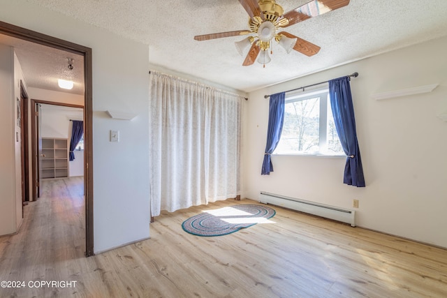 empty room featuring a textured ceiling, wood-type flooring, ceiling fan, and a baseboard radiator