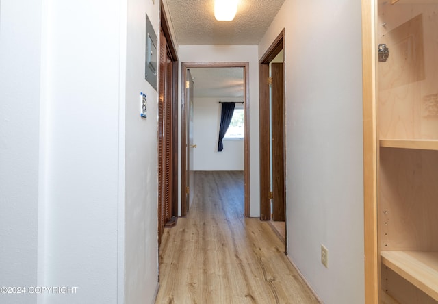 hall featuring light hardwood / wood-style flooring and a textured ceiling