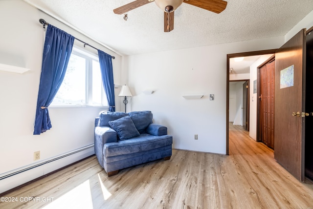 living area with light hardwood / wood-style flooring, a textured ceiling, ceiling fan, and a baseboard radiator