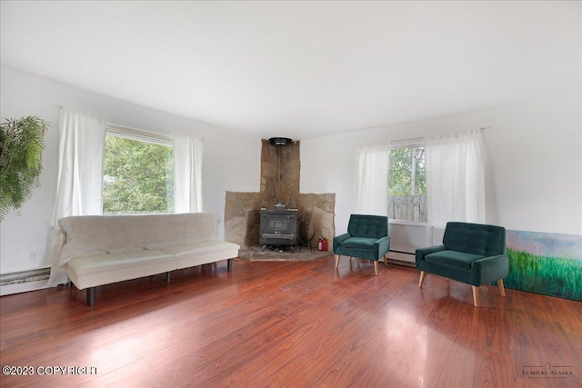 living area with a wood stove, baseboard heating, and hardwood / wood-style floors