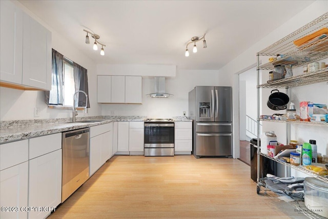 kitchen featuring white cabinetry, light hardwood / wood-style flooring, wall chimney range hood, stainless steel appliances, and track lighting