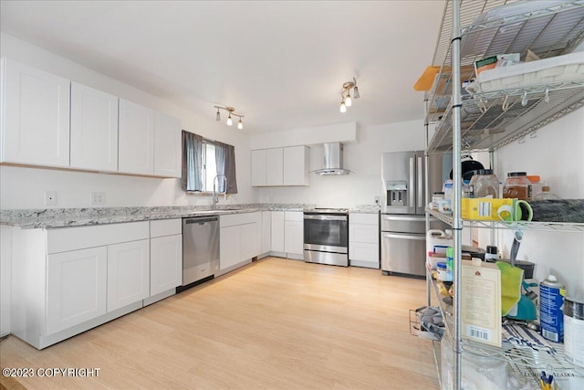 kitchen with white cabinetry, light hardwood / wood-style flooring, wall chimney range hood, and stainless steel appliances