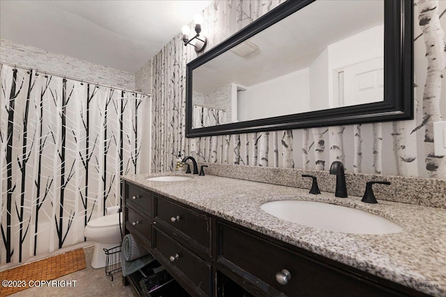 bathroom with dual vanity, tile patterned flooring, and toilet