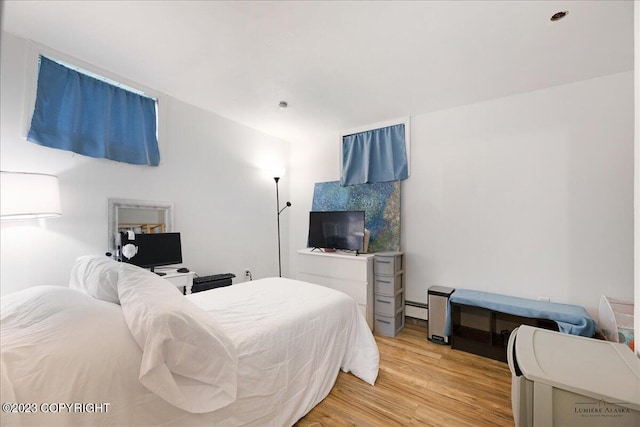 bedroom with light hardwood / wood-style floors and baseboard heating