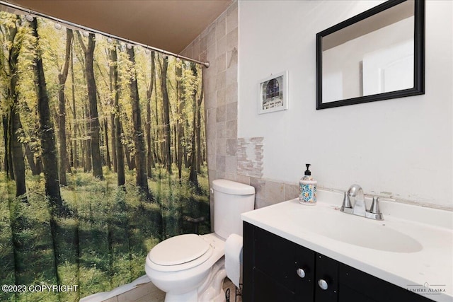 bathroom featuring vanity, tile walls, and toilet