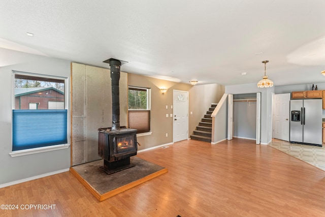 unfurnished living room with light hardwood / wood-style flooring, a wood stove, and plenty of natural light