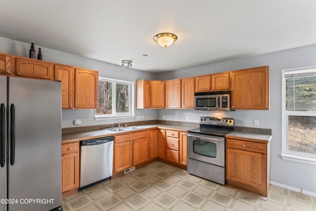 kitchen featuring sink, plenty of natural light, light tile flooring, and stainless steel appliances