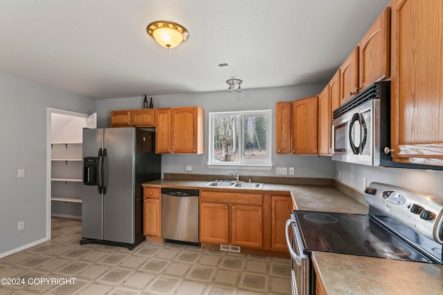 kitchen with sink, stainless steel appliances, and light tile flooring