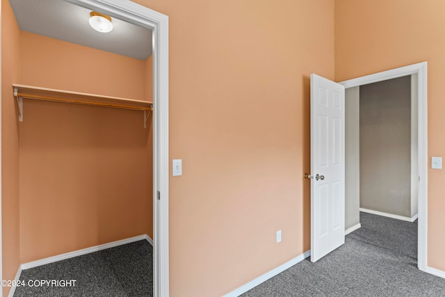 unfurnished bedroom featuring dark colored carpet and a closet