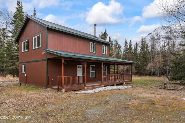 rear view of house featuring a mountain view and a porch