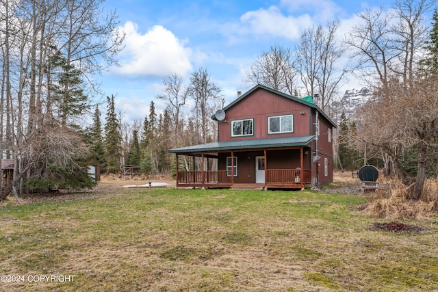 rear view of property with covered porch and a lawn