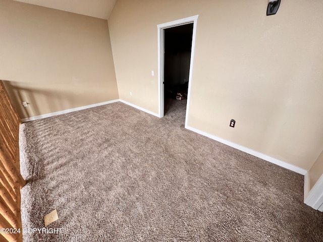 unfurnished bedroom featuring lofted ceiling, baseboards, and carpet flooring