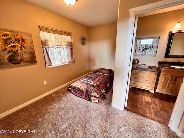 bedroom with dark carpet, a sink, and baseboards