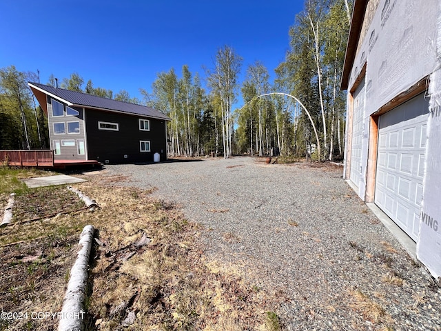 view of yard featuring a garage, driveway, and a wooden deck