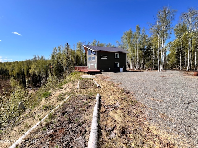 exterior space with metal roof, a forest view, and a wooden deck