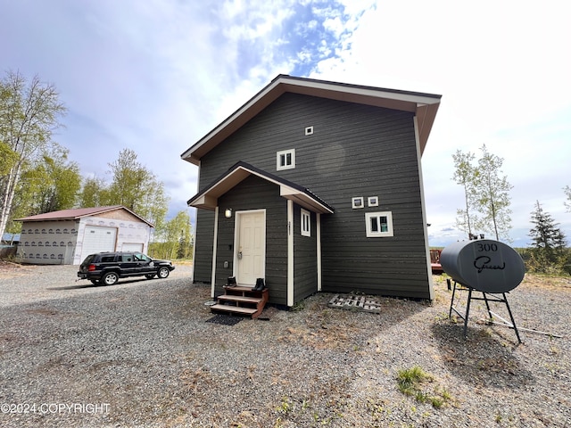 view of front facade with entry steps, a detached garage, and an outbuilding