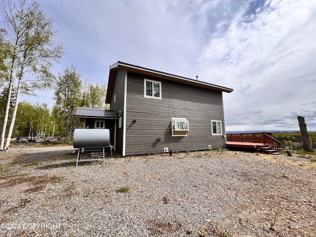 back of property featuring a deck, metal roof, and heating fuel