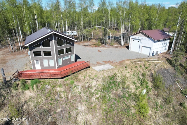 view of yard with a garage, a forest view, a deck, and an outdoor structure