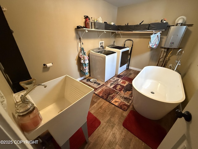 clothes washing area featuring laundry area, dark wood-style flooring, a sink, baseboards, and washing machine and clothes dryer