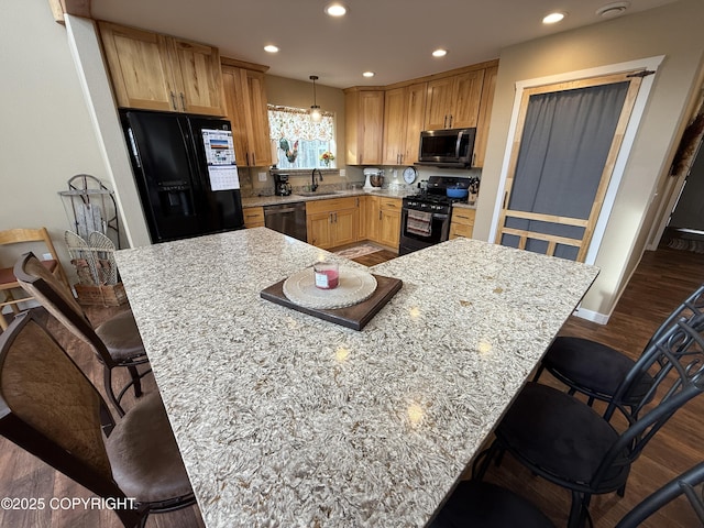 kitchen with a breakfast bar area, a sink, black appliances, and recessed lighting