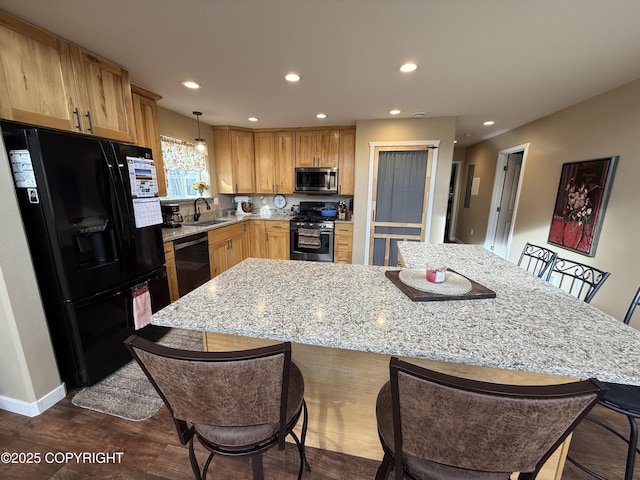 kitchen with light stone counters, recessed lighting, a breakfast bar, a sink, and black appliances