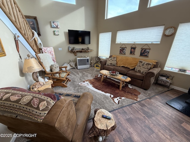 living room featuring a high ceiling, wood finished floors, and baseboards