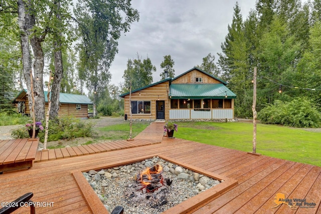 wooden terrace featuring an outdoor fire pit and a lawn