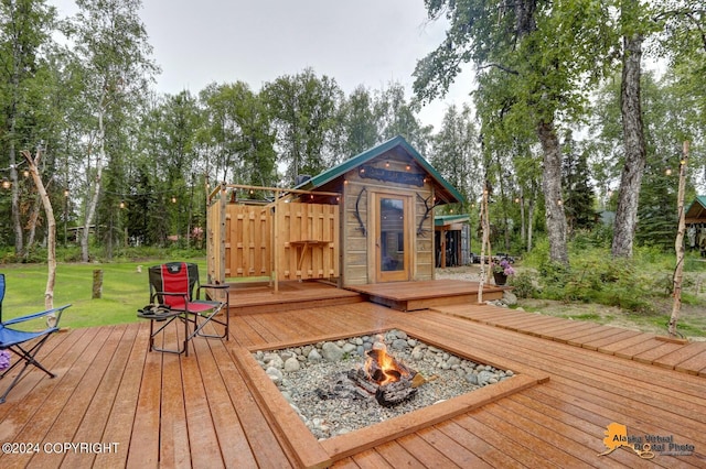 wooden deck featuring an outdoor fire pit and a lawn