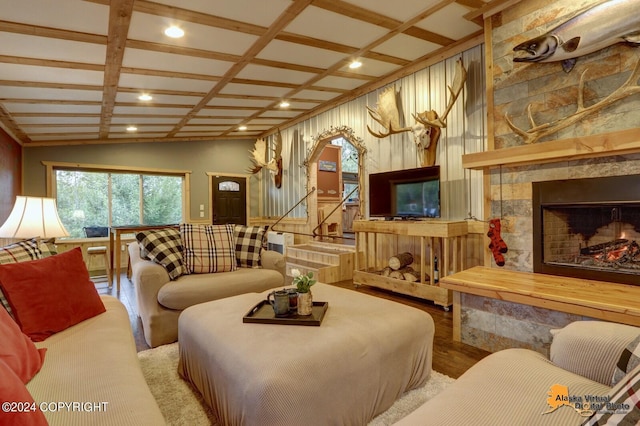 living room featuring a stone fireplace and coffered ceiling