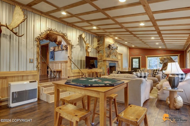 dining area featuring coffered ceiling, heating unit, wood-type flooring, a stone fireplace, and lofted ceiling